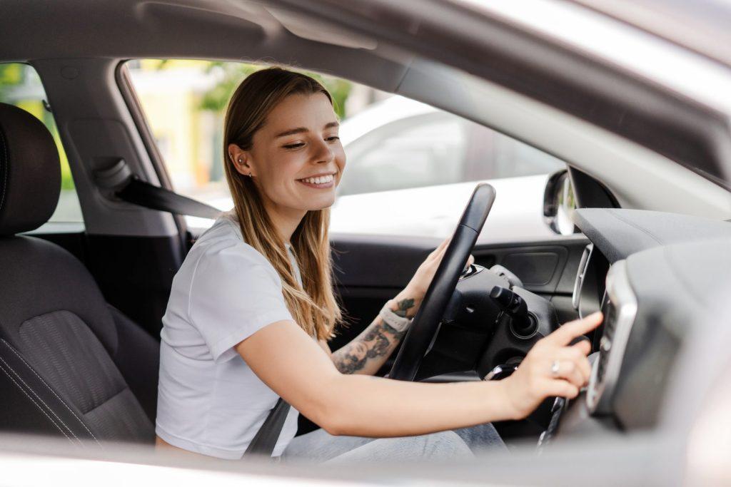 Smiling young woman sitting in her new car after car shopping