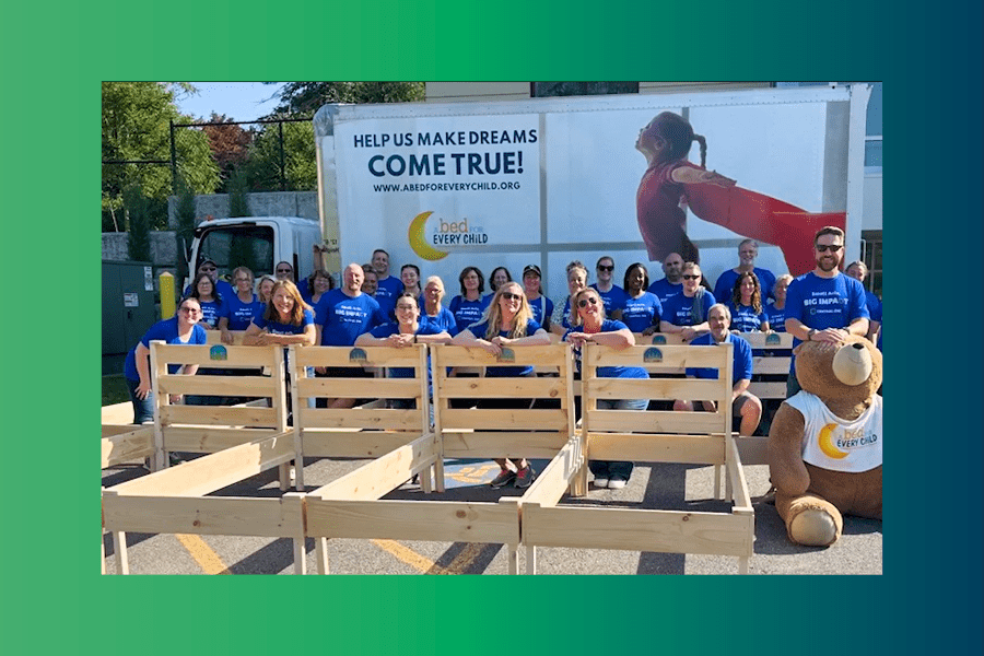 A group of Central One employee volunteers stand behind the beds they build for the Build-A-Bed event