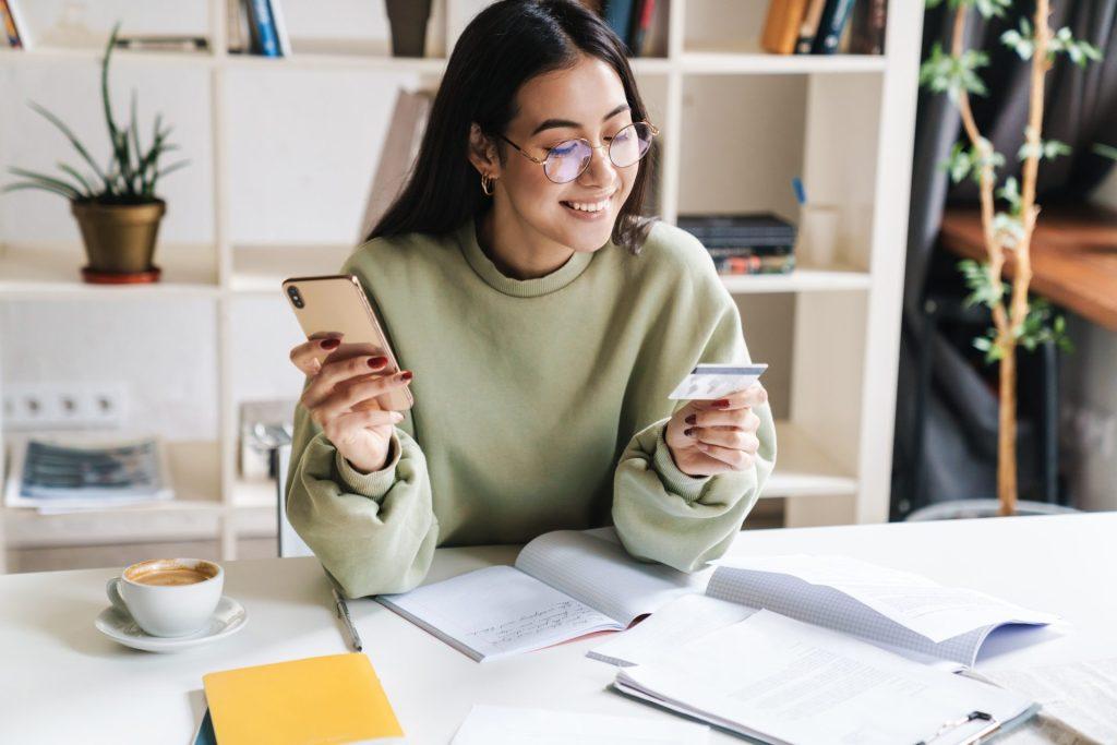 Girl looking at her card and phone with a smile.